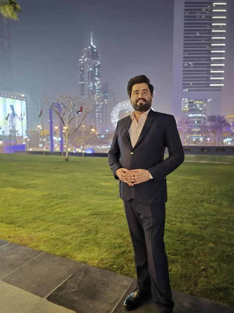 Ayaz Akram Awan at night in Dubai, with the city skyline behind him